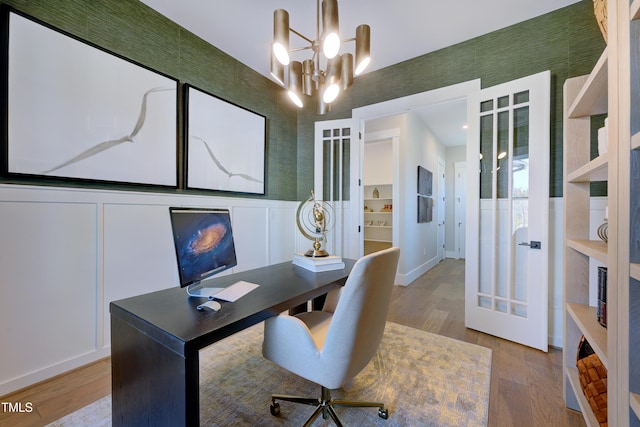 home office with light wood finished floors, a chandelier, wainscoting, and baseboards