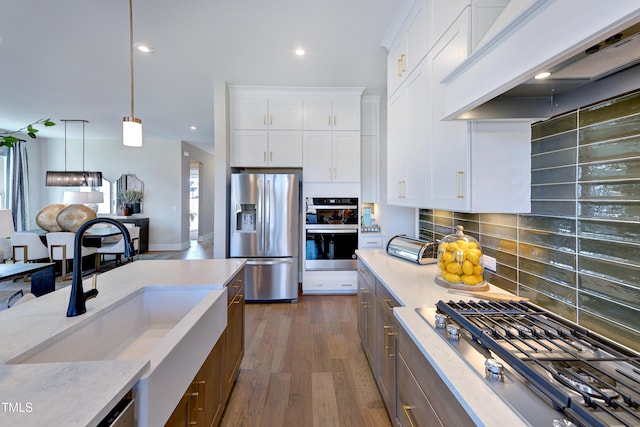 kitchen with stainless steel appliances, a sink, custom exhaust hood, light stone countertops, and tasteful backsplash