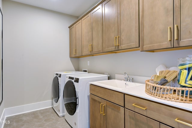 laundry area featuring washing machine and dryer, cabinet space, and baseboards