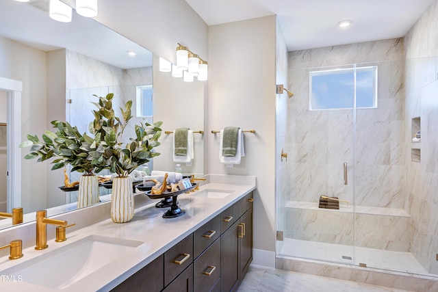 bathroom with a marble finish shower and double vanity