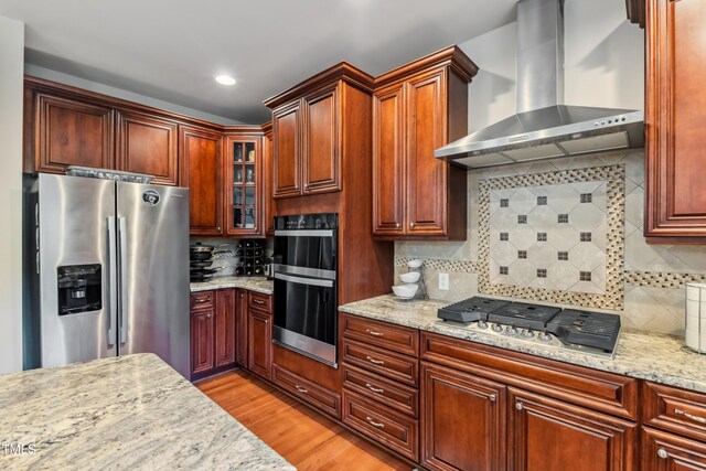 3404 Mount Pisgah Way, Cary, NC 27519 - kitchen with wall chimney exhaust hood, stainless steel appliances, backsplash, glass insert cabinets, and light wood finished floors