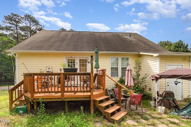 rear view of property featuring a wooden deck and roof with shingles