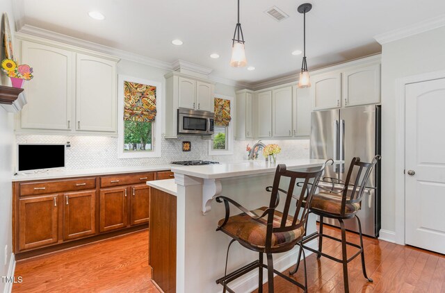 241 Serenity Hill Cir, Chapel Hill, NC 27516 - kitchen with appliances with stainless steel finishes, light wood finished floors, a breakfast bar area, light countertops, and decorative backsplash