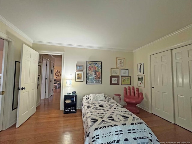 bedroom with wood finished floors, crown molding, and a closet