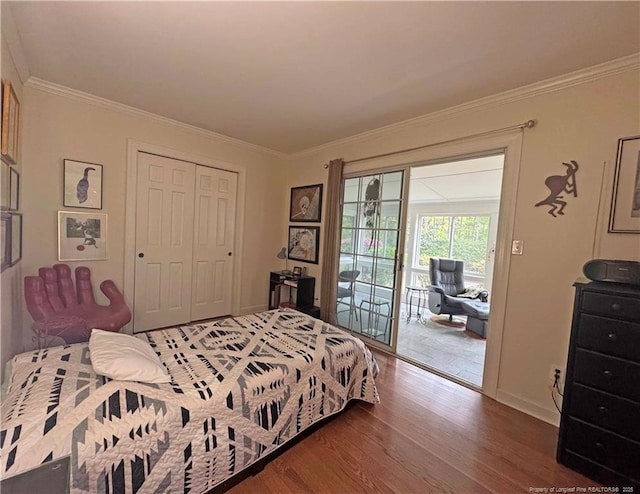 bedroom with access to exterior, wood finished floors, crown molding, a closet, and baseboards
