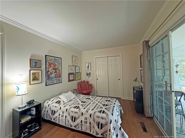 bedroom featuring wood finished floors, crown molding, and a closet