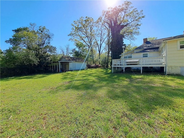 view of green lawn with a deck, an outdoor structure, and a storage unit