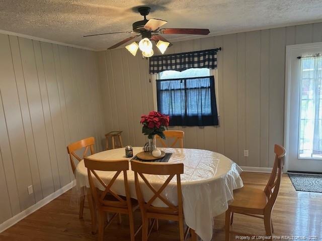 dining area featuring a textured ceiling, light wood-style floors, a ceiling fan, and baseboards