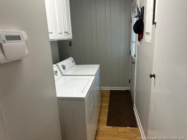 washroom featuring washer and clothes dryer, light wood finished floors, cabinet space, and baseboards