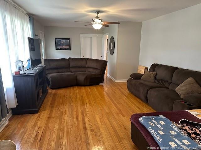 living room featuring ceiling fan, light wood-type flooring, and baseboards