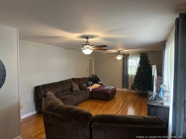 living room featuring wood finished floors, a ceiling fan, and baseboards