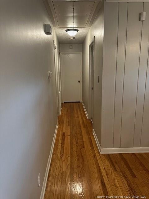 hallway with attic access, wood finished floors, and baseboards
