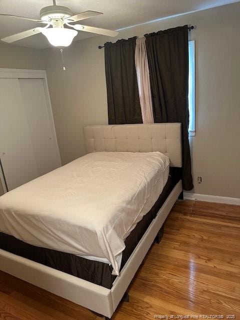 bedroom featuring wood finished floors, baseboards, a closet, and a ceiling fan
