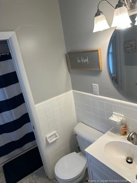 full bath with tile walls, toilet, wainscoting, vanity, and a shower with shower curtain