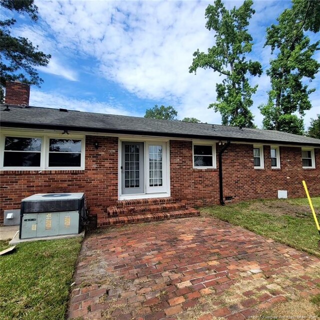505 W 30th St, Lumberton, NC 28358 - back of property with central AC unit, brick siding, a patio area, and entry steps