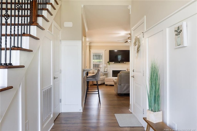 foyer entrance with dark wood finished floors, a fireplace, stairs, and ceiling fan