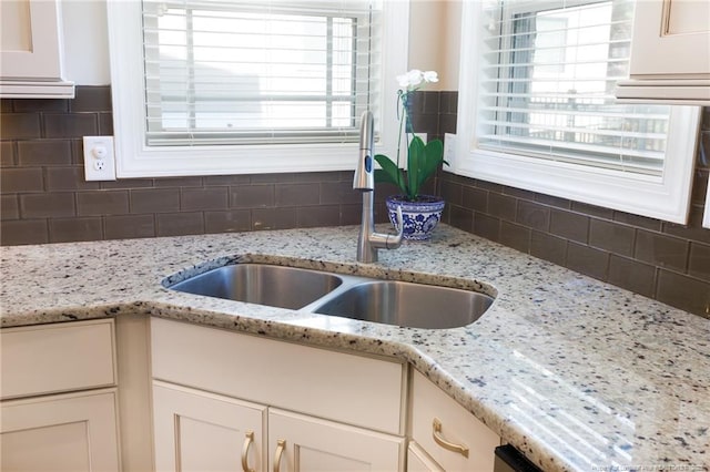 kitchen with a sink, white cabinetry, and tasteful backsplash