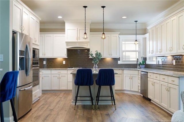 kitchen with appliances with stainless steel finishes, white cabinetry, a center island, and ornamental molding