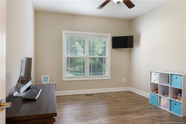 unfurnished office with ceiling fan, wood finished floors, and baseboards