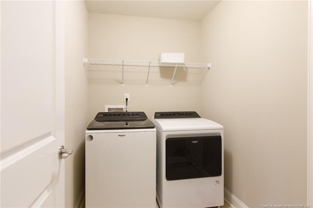washroom with washing machine and clothes dryer and baseboards