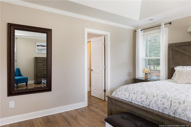 bedroom featuring baseboards, wood finished floors, and crown molding