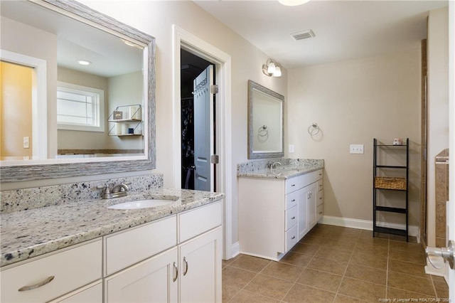 full bathroom featuring two vanities, tile patterned flooring, baseboards, and a walk in closet