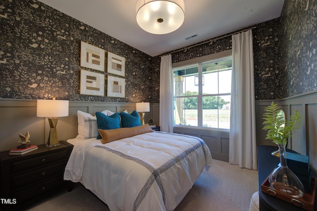 carpeted bedroom with wallpapered walls and wainscoting