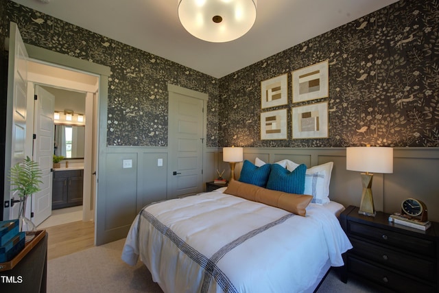 bedroom featuring wallpapered walls, a wainscoted wall, wood finished floors, and a decorative wall