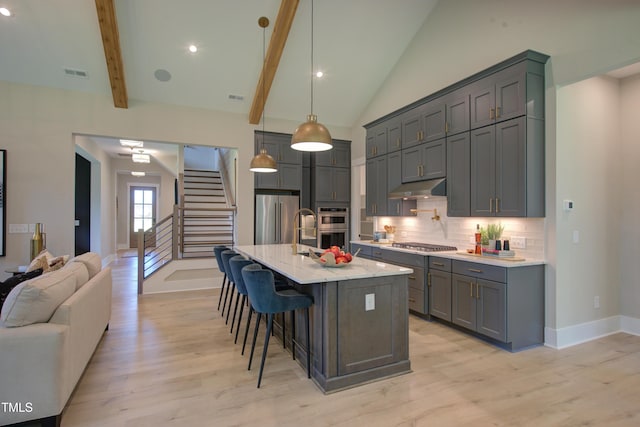 kitchen featuring appliances with stainless steel finishes, under cabinet range hood, light wood-style floors, decorative backsplash, and recessed lighting
