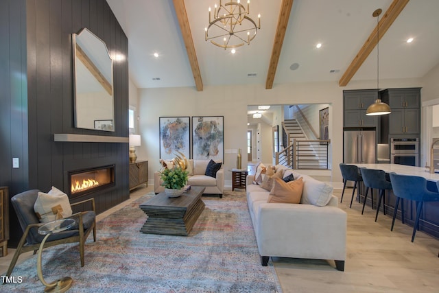 living area with a fireplace, stairway, plenty of natural light, light wood-style floors, and beamed ceiling