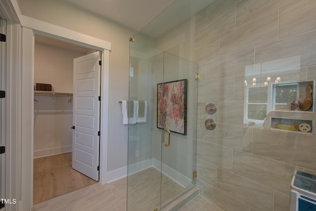 full bathroom featuring a shower stall, a spacious closet, and baseboards