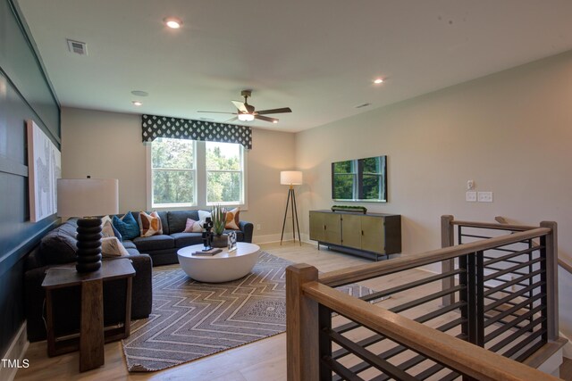 living area featuring wood finished floors, a ceiling fan, recessed lighting, and baseboards