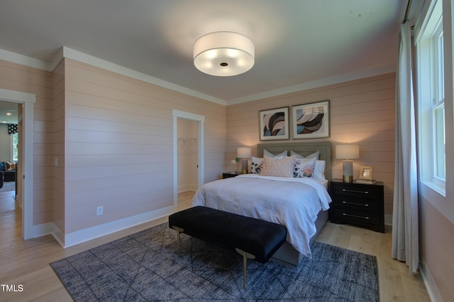 bedroom featuring light wood finished floors and wooden walls