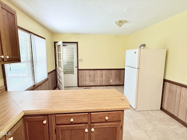 174 Carolina Dr, Reidsville, NC 27320 - kitchen with freestanding refrigerator, wainscoting, a textured ceiling, a peninsula, and wood walls
