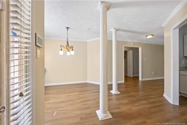 spare room featuring crown molding, wood finished floors, baseboards, a textured ceiling, and a chandelier