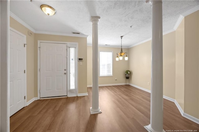 entrance foyer with decorative columns, wood finished floors, ornamental molding, baseboards, and a textured ceiling