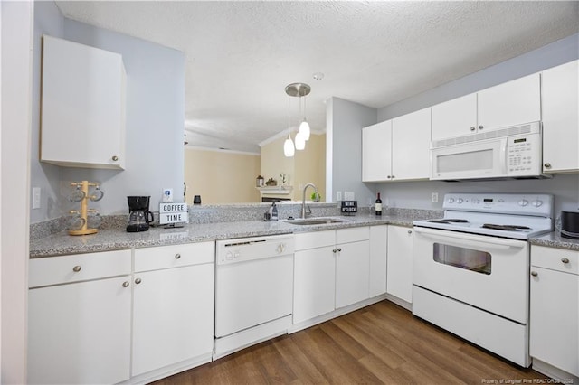 kitchen with white appliances, a sink, dark wood finished floors, white cabinets, and ornamental molding
