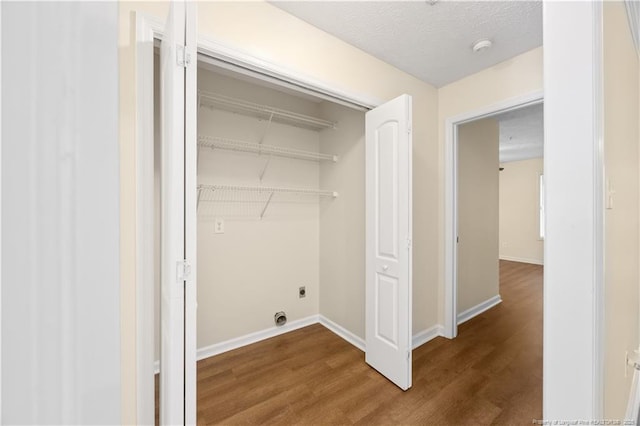clothes washing area featuring wood finished floors, baseboards, and electric dryer hookup