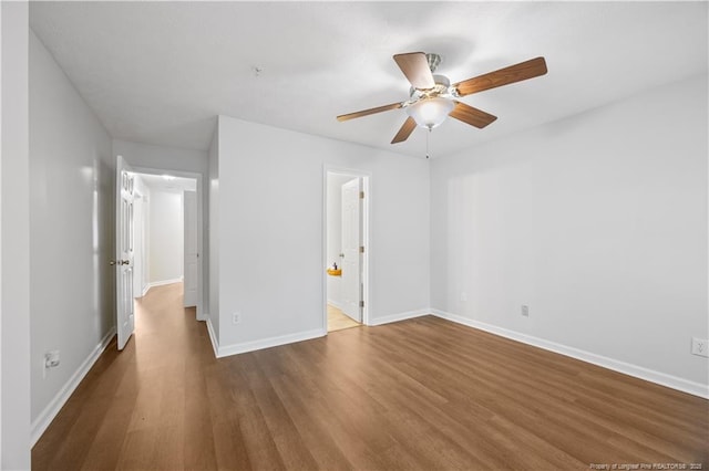 unfurnished bedroom featuring wood finished floors, baseboards, ceiling fan, and ensuite bath