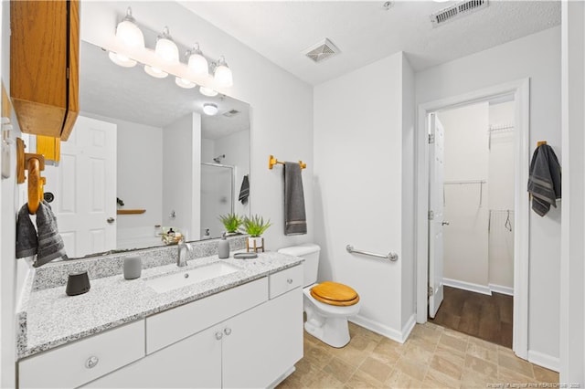 bathroom featuring an enclosed shower, a spacious closet, toilet, vanity, and baseboards