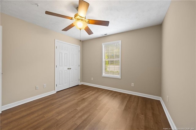 unfurnished bedroom with wood finished floors, baseboards, a closet, a ceiling fan, and a textured ceiling