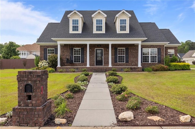 new england style home featuring brick siding, a porch, and roof with shingles