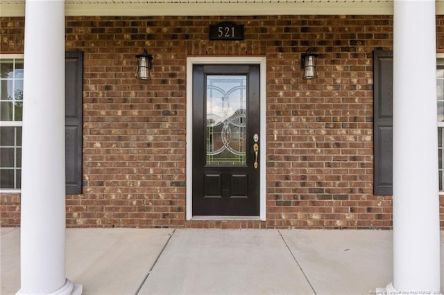 entrance to property featuring brick siding and a porch