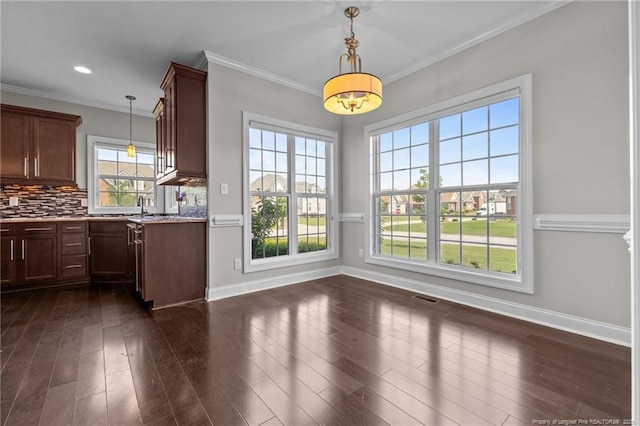 kitchen with pendant lighting, baseboards, backsplash, dark wood-style flooring, and ornamental molding