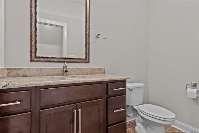 bathroom featuring baseboards, toilet, and vanity