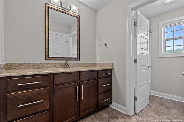 bathroom featuring baseboards, vanity, and stone finish flooring