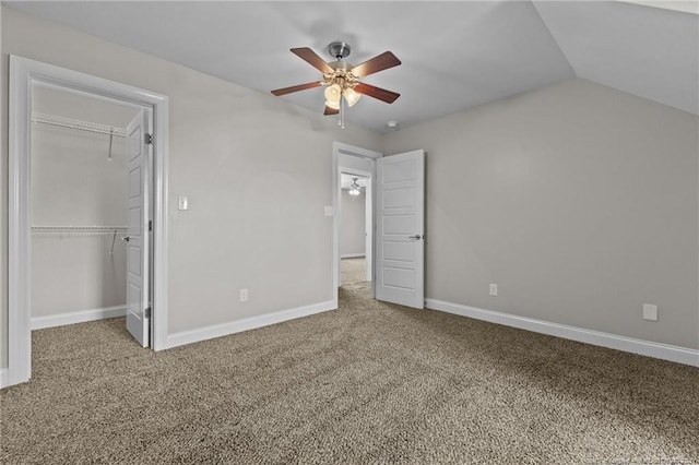 unfurnished bedroom with carpet floors, a closet, baseboards, ceiling fan, and a spacious closet