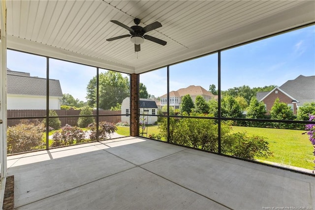unfurnished sunroom with a ceiling fan, a residential view, and healthy amount of natural light