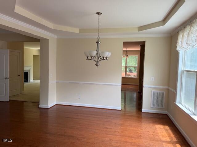 5804 Claribel Ct, Raleigh, NC 27612 - unfurnished dining area with a tray ceiling, a chandelier, wood finished floors, baseboards, and crown molding