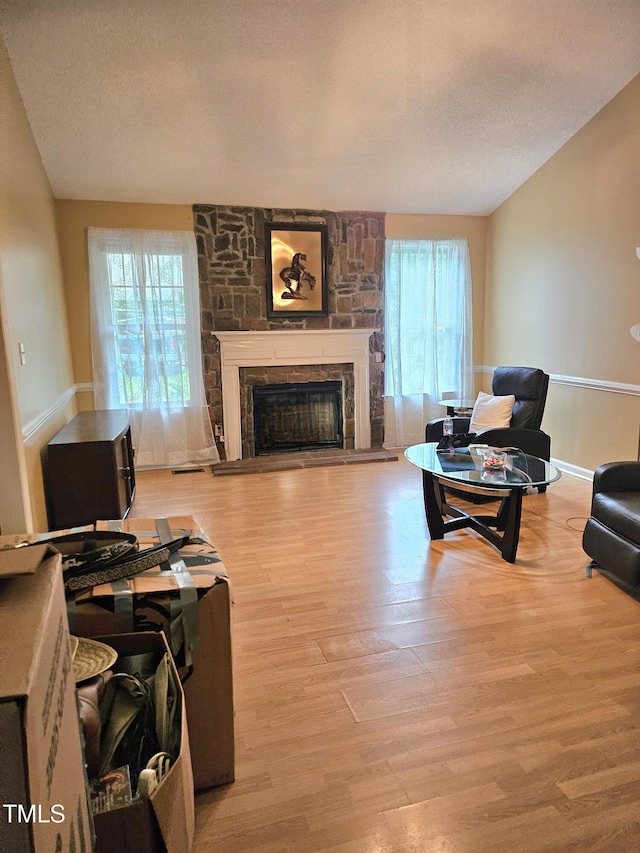 1360 Honeycutt Rd, Willow Springs, NC 27592 - living area with wood finished floors, a stone fireplace, baseboards, and a textured ceiling